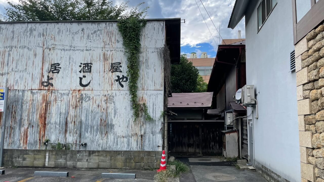 山形市七日町の大通りから少し外れた場所にあります。「居酒屋よしや」の文字と建物の間を通り、